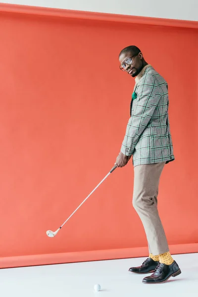 Homem americano africano na moda jogando golfe, no vermelho — Fotografia de Stock