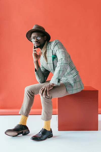 Hombre afroamericano de moda hablando en el teléfono inteligente, en rojo - foto de stock