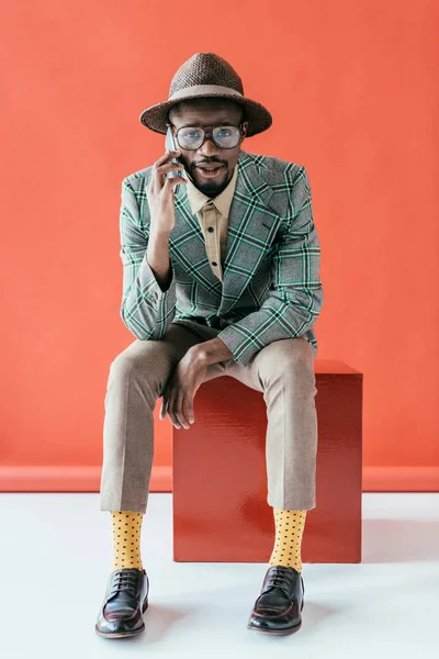 Hombre afroamericano guapo de moda hablando en el teléfono inteligente, en rojo - foto de stock