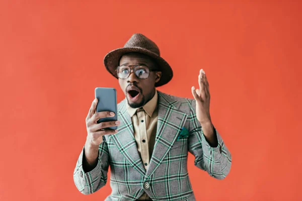 Chocado afro-americano homem usando smartphone, isolado no vermelho — Fotografia de Stock