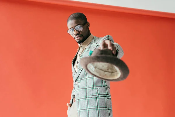 Messa a fuoco selettiva di bell'uomo afroamericano in posa con cappello, sul rosso — Foto stock