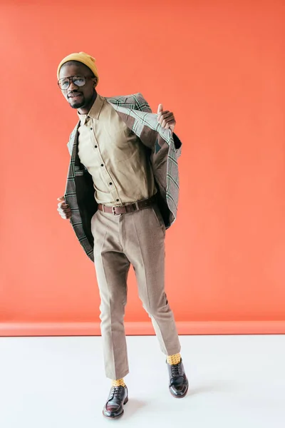 African american man in trendy vintage jacket, on red — Stock Photo