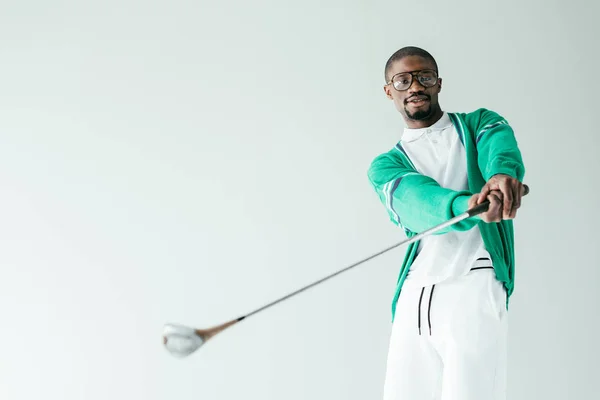 Стильный африканский американец в ретро спортивной одежде играет в гольф, изолированный на белом — стоковое фото
