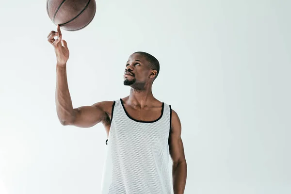Красивий афроамериканський баскетболіст обертається м'яч на пальці, ізольований на білому — стокове фото