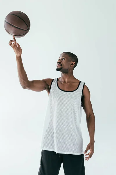 Atlético africano americano baloncesto jugador de spinning bola en dedo, aislado en blanco - foto de stock