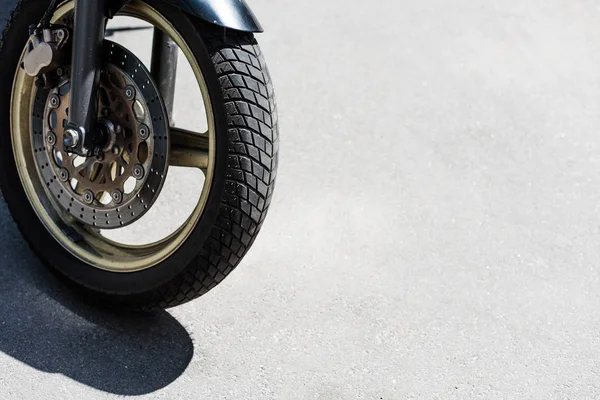 Front wheel with black tire of motorcycle on street — Stock Photo