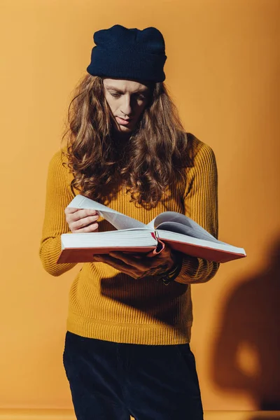 Homem elegante bonito com livro de leitura de cabelo longo, em amarelo — Fotografia de Stock