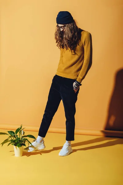 Fashionable elegant man standing near plant, on yellow — Stock Photo