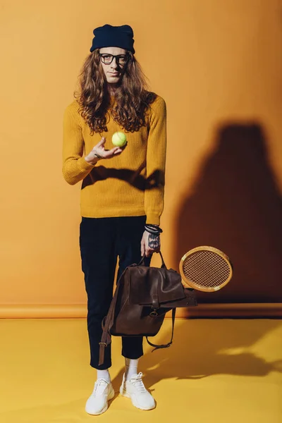 Hombre elegante con pelota de tenis y raqueta de madera, en amarillo - foto de stock
