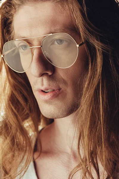 El retrato del hombre a la moda con el pelo largo en las gafas de estilo, sobre negro - foto de stock