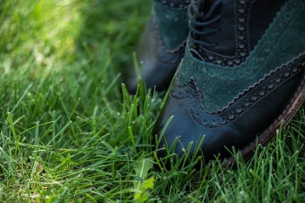 Selektiver Fokus schwarzer Lederschuhe auf grünem Gras — Stockfoto