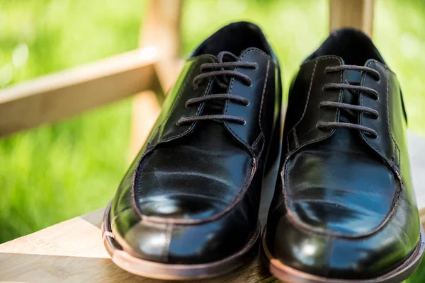 Selektiver Fokus schwarzer Lederschuhe auf Holztreppen mit grün verschwommenem Hintergrund — Stockfoto