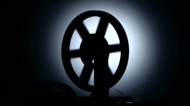 Siluet karanlık bir stüdyoda. Bobin film projektör makara film