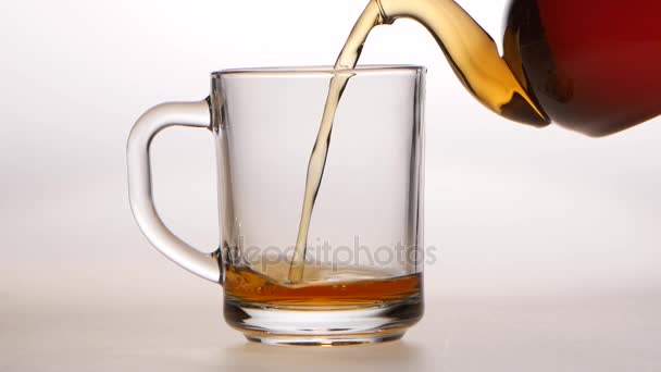Černý čaj se sype z konvice do šálku skla — Stock video