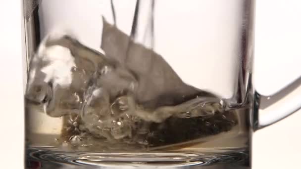 Água fervente é derramada em xícara com saco de chá de pirâmide — Vídeo de Stock