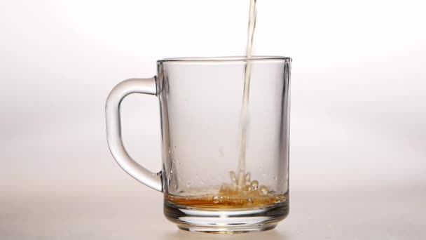 Jet of hot tea fills the glass cup. Slow motion — Stock Video