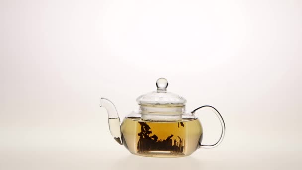 infuser le thé feuille dans une théière en verre transparent. Fond blanc 