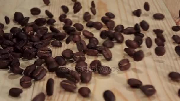 Graan van verse koffie valt op de tafel en kruimels. Close-up. Slow motion — Stockvideo