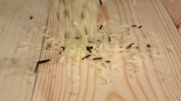 Reis fällt auf einen Holztisch und verschüttet sich. Zeitlupe. Nahaufnahme — Stockvideo