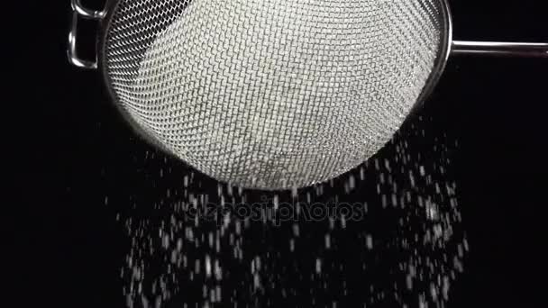 Mehl in Zeitlupe durch ein Sieb auf schwarzem Hintergrund sieben — Stockvideo