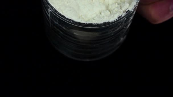 Hombre vertiendo harina de la taza sobre fondo negro. Movimiento lento — Vídeos de Stock