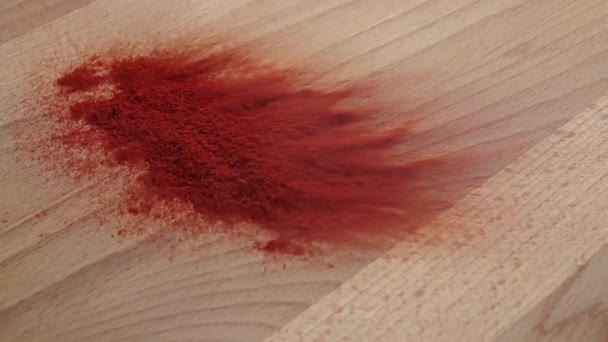 Un puñado de pimiento rojo se desmorona en la mesa de madera, en cámara lenta — Vídeos de Stock