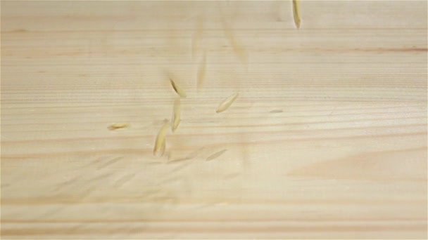 Зерна пшеницы в замедленной съемке падают на деревянный стол. Крупный план — стоковое видео