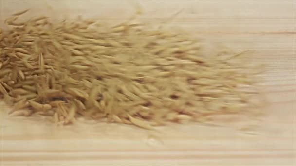 Пшеничные зерна падают на деревянный стол, замедленная съемка. Вид сверху — стоковое видео