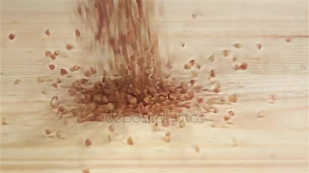 Ruwe graan boekweit vallen op tafel, slow-motion. Bovenaanzicht — Stockvideo