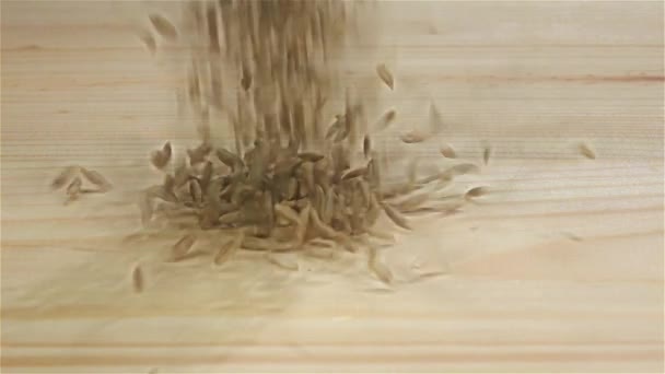 Зерна пшеницы падают на деревянный стол, замедленная съемка. Вид сверху — стоковое видео