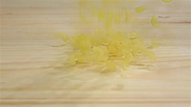 Паста падає на купу макаронних виробів, дерев'яний фон. Повільний рух — стокове відео