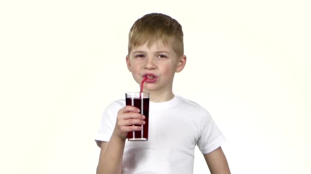 Мальчик пьет гранатовый сок и закрывает глаза от насложения. Белый фон. Медленное движение — стоковое видео