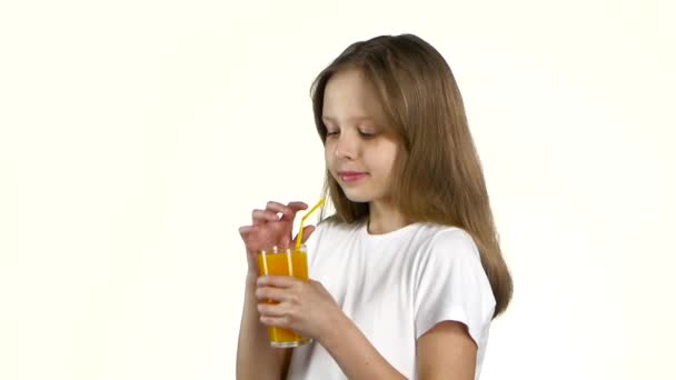 Маленька дівчинка п'є апельсиновий сік і показує уроки. Білий фон. Повільний рух — стокове відео