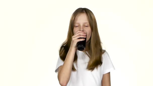 La niña bebe jugo de granada, se lame los labios. Fondo blanco. Movimiento lento — Vídeos de Stock