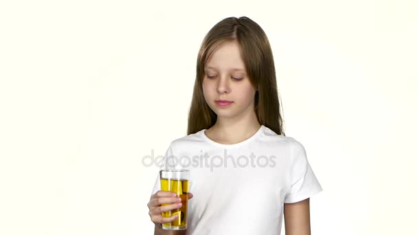 Lilla flickan dricker äppeljuice och beundrar det. Vit bakgrund. Slow motion — Stockvideo