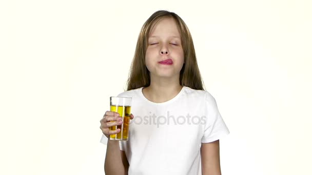 La fille boit du jus de pomme, lèche ses lèvres après le jus. Fond blanc. Mouvement lent — Video