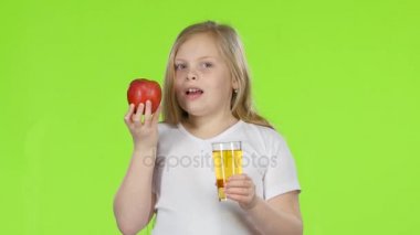 Küçük kız içecekler cam suyu ve elma tutar. Yeşil ekran