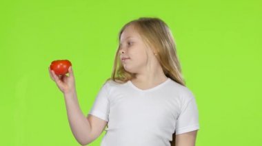 Küçük kız domates görünüyor, o çok beğendiği ve baş parmak işareti gösterir. Yeşil ekran