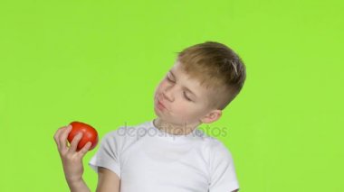 Küçük boy domates tutan o burnunu çekmek ve baş parmak işareti gösterir. Yeşil ekran