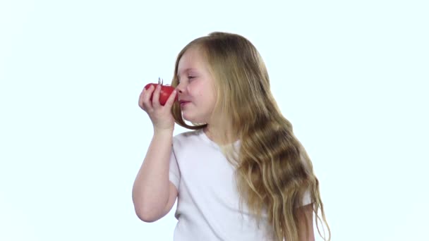 Petite fille regarde une tomate, l'admire et sourit. Fond blanc. Mouvement lent — Video