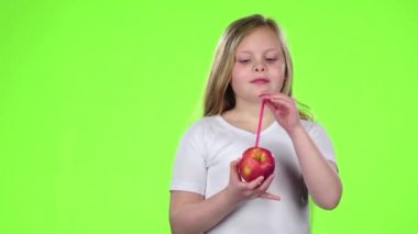 Küçük kız bir elma onun elinde tutan ve suyu içiyor. Yeşil ekran. Ağır çekim
