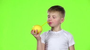 Çocuk bir limon limon suyu içme bir saman tutar ve baş parmak işareti gösterir. Yeşil ekran. Ağır çekim