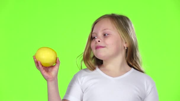 Little girl is holding a lemon and sniffing it. Green screen. Slow motion — Stock Video