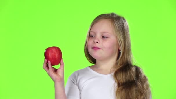 La niña huele y muerde una manzana. Pantalla verde. Movimiento lento — Vídeo de stock
