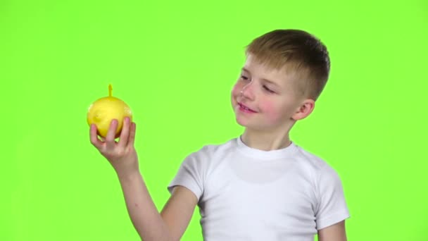 En lille drengs citron med et sugerør og drikker juice af det. Grøn skærm. Langsom bevægelse – Stock-video