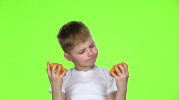Malý chlapec olizuje plátky pomeranče. Zelená obrazovka. Zpomalený pohyb — Stock video