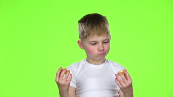 Small boy holds a slice of a lemon licks and curls from acid. Green screen. Slow motion — Stock Video