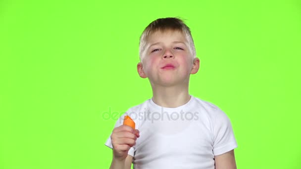 Kinder beißen in eine Karotte und zeigen den Daumen nach oben. Green Screen. Zeitlupe — Stockvideo