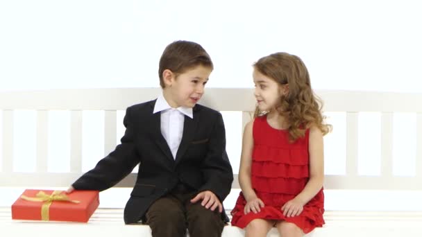 Little boy takes a pair of pants and gives the girl in return she kisses him on the cheek. White background — Stock Video