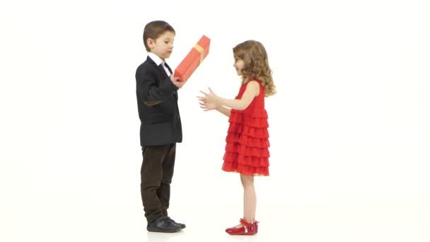 Little boy gives his girlfriend a gift, she kisses him gently on the cheek. White background — Stock Video